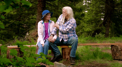 Ami And Billy Brown holding hands on a bench in the woods