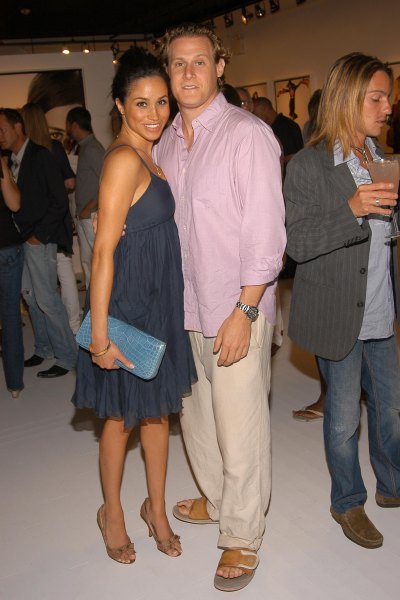 Meghan Markle wearing a gray dress with Trevor Engelson wearing a pink shirt