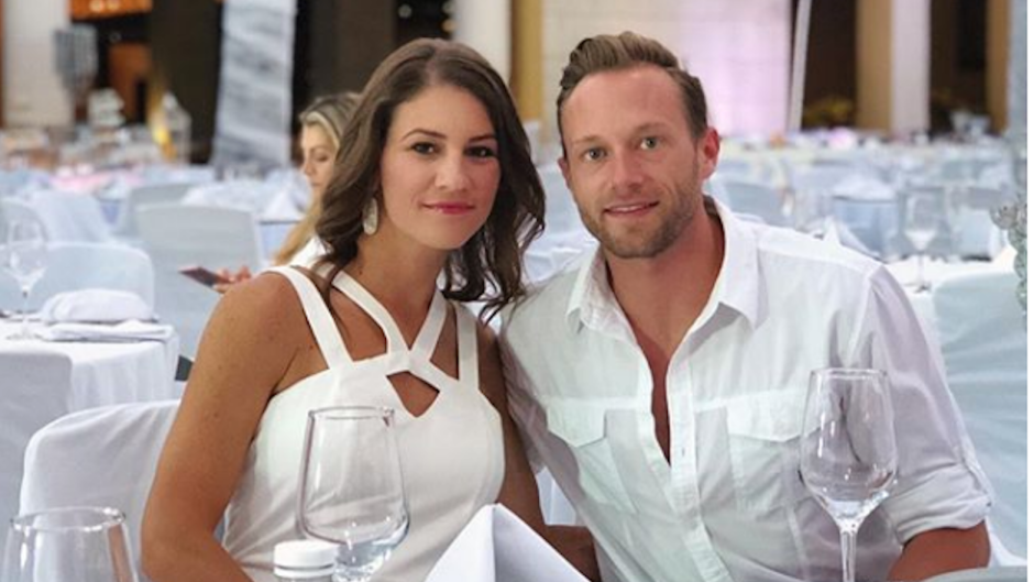 Danielle wearing white with her husband, Adam Busby, also wearing white