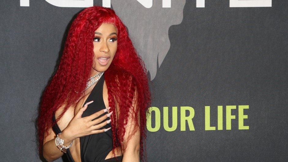 Cardi B wearing a black outfit with red hair at a party