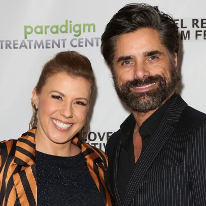 Jodie Sweetin wearing a striped shirt with John Stamos in a black suit