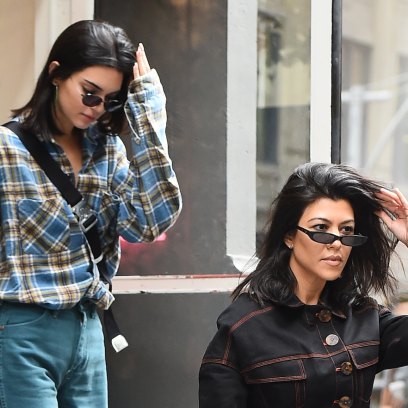 Kourtney Kardashian Wearing a Black Shirt with Sunglasses While Kendall Jenner In Plaid Walks Behind Her