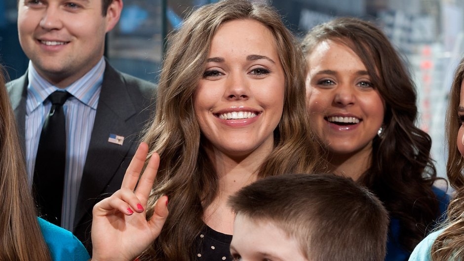 Jessa Duggar gives the peace sign. Shes's wearing a black shirt with beige polka dots.