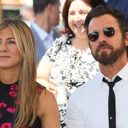 Jennifer Aniston Wearing a Black Dress With Red on It With Justin Theroux Wearing a White Shirt With Sunglasses