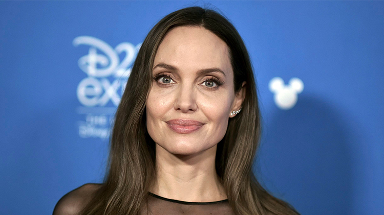 angelina jolie stuns in a black knee length dress with a high thigh slit and a sheer neckline and sleeves at the d23 red carpet