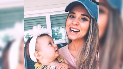 jinger duggar wears pink shirt and denim baseball cap while holding daughter felicity who is wearing a white floral headband jinger duggar coffee la instagram