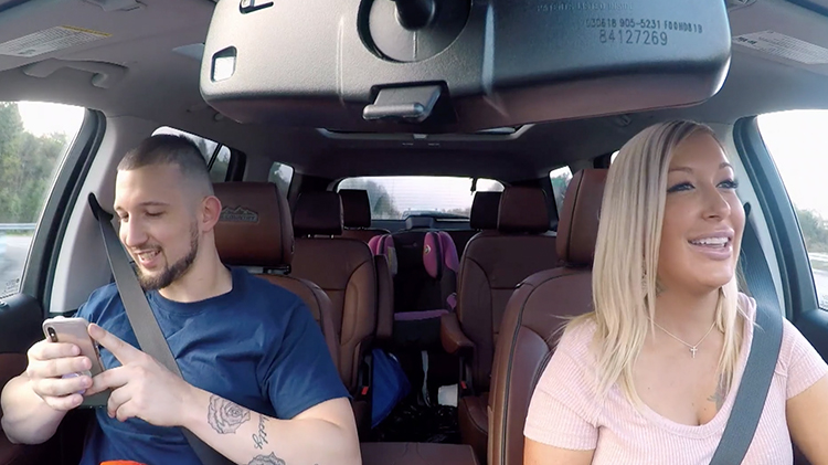 love after lockup star shane sits in a car wearing a blue t shirt and holding lacey's phone while lacey wears a pink shirt behind the wheel love