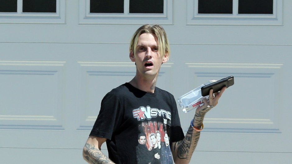 Aaron Carter Wearing Black Outfit Walking Barefoot Outside a Home With His Friend