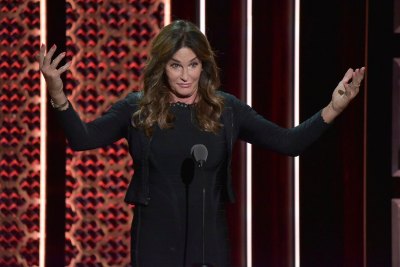 Caitlyn Jenner Standing in Front of An Audience at Comedy Central Wearing a Black Dress