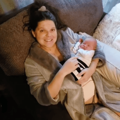 amy duggar king resting and holding her newborn son dax on a couch