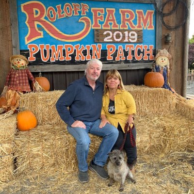 amy roloff with boyfriend chris marek and dog in front of roloff farm sign
