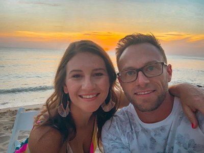 adam and danielle busby smiling in front of a sunset