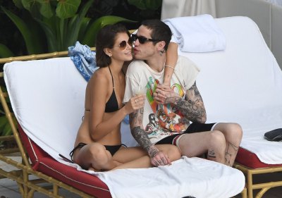 pete davidson wears black and white swim trunks with a graphic tee and sunglasses while his new girlfriend, kaia gerber, wore a black bikini as they packed on pda by a pool on vacation