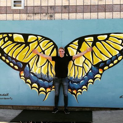 micah plath in front of butterfly mural