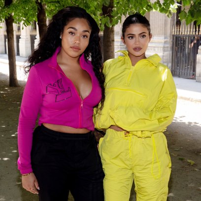 Jordyn Woods wearing a pink shirt and Kylie Jenner wearing a yellow track suit