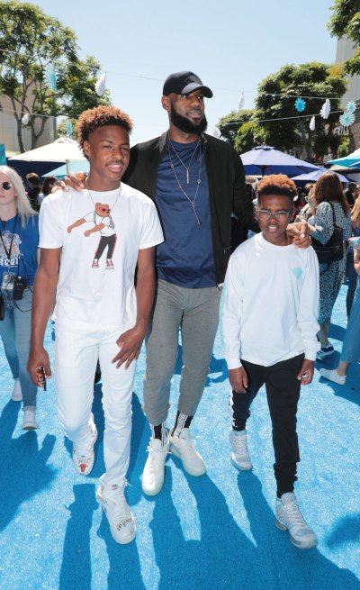 Lebron James walking with his sons Bryce and Bronny on a blue carpet