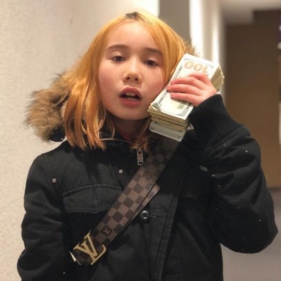Lil Tay holding a wad of cash and wearing a black winter coat
