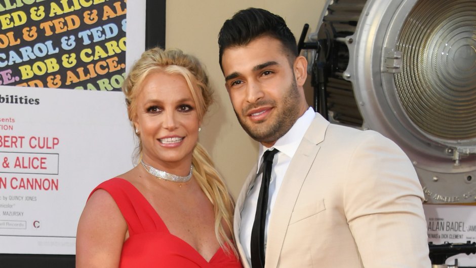 Britney Spears wearing a red dress and black pump heels and Sam Asghari wearing a beige suit on the red carpet