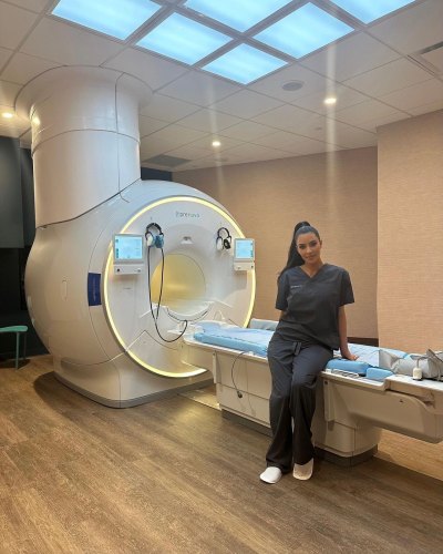 Kim Kardashian wearing black hospital scrubs standing in front of a body scan machine