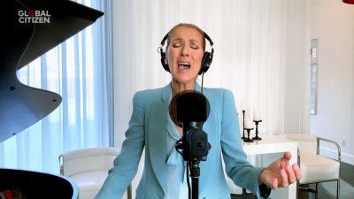 Celine Dion singing in front of a mic while wearing a baby blue suit.