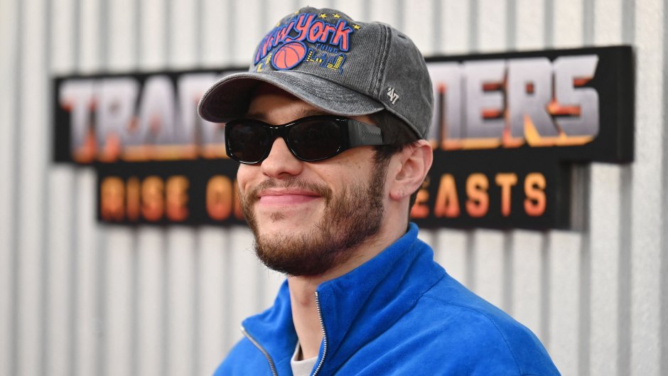 Pete Davidson wears a blue track jacket, baseball cap and sunglasses
