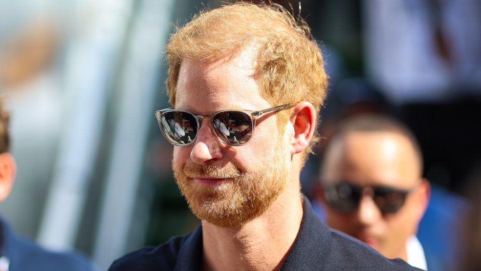 Prince Harry wears a dark colored polo and sunglasses.