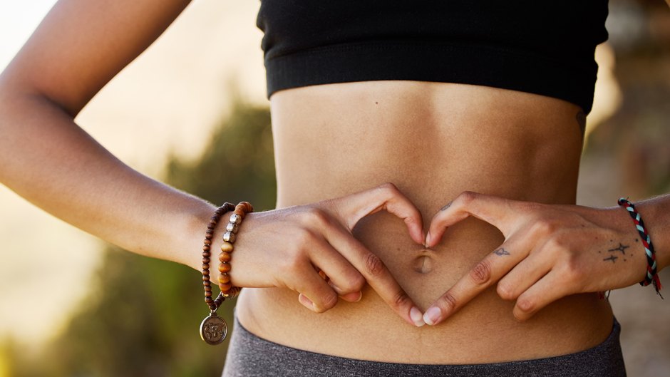 Cropped shot of a young woman forming a heart shape over her stomach
