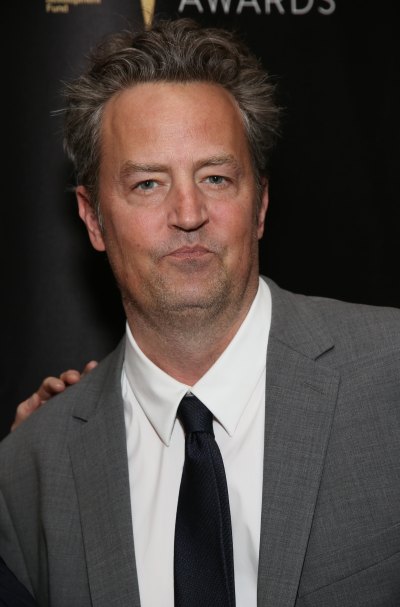 Matthew Perry wears a gray suit and a black tie