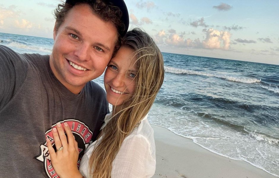 jeremiah duggar and his wife hannah smile at camera on the beach with ocean behind them