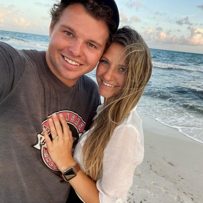 jeremiah duggar and his wife hannah smile at camera on the beach with ocean behind them
