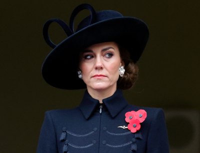 Kate Middleton wearing a navy ensemble with a red broach and black hat