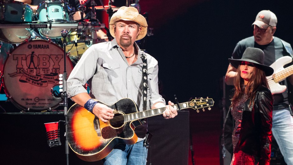 Toby Keith holds a guitar on stage at the 2021 iHeartCountry Festival.