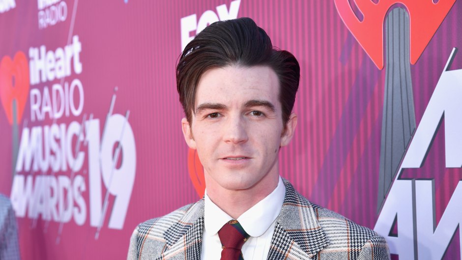 Drake Bell wearing a plaid suit and burgundy tie